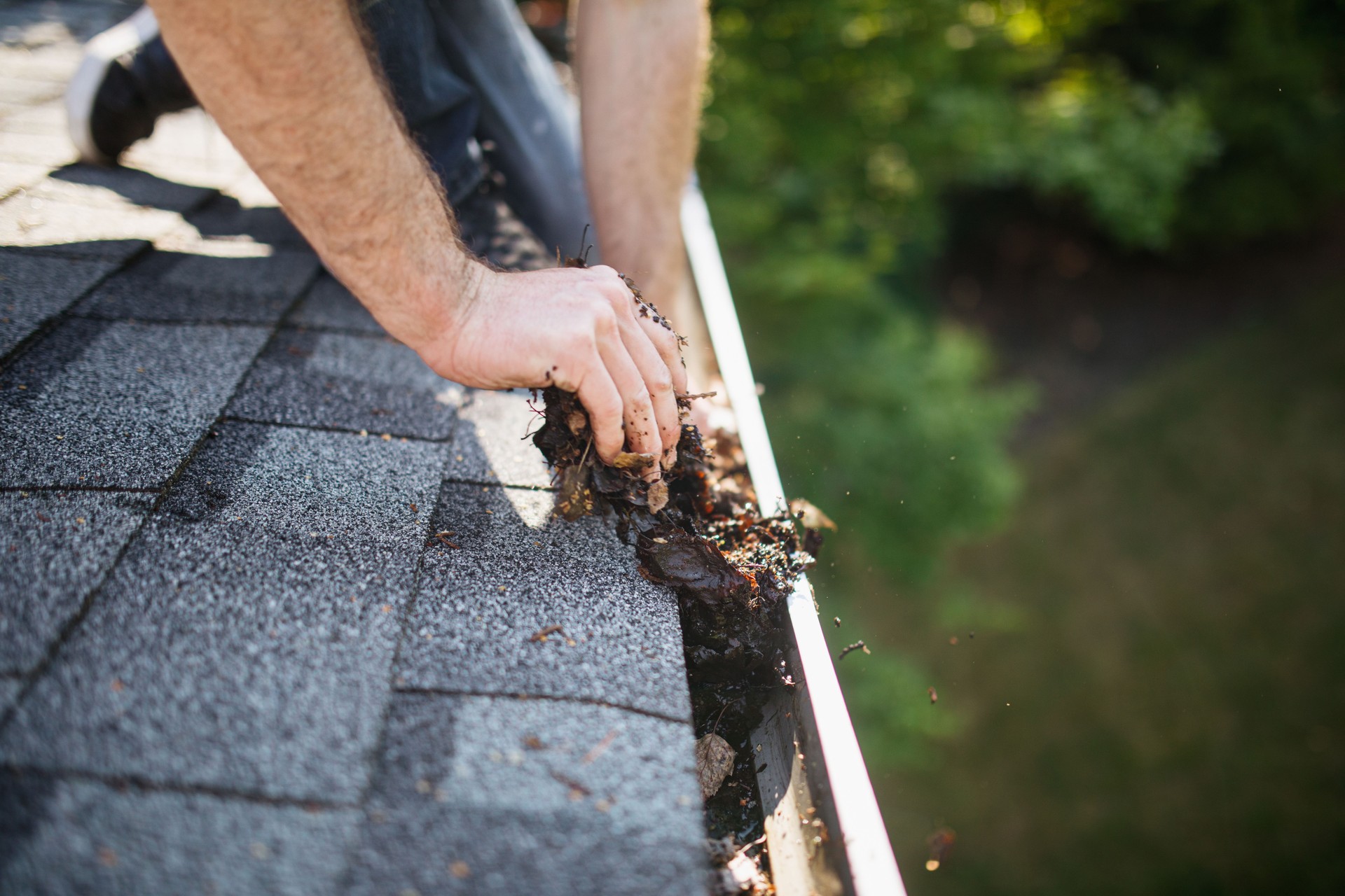 Man Cleaning Out Roof Gutters on Home